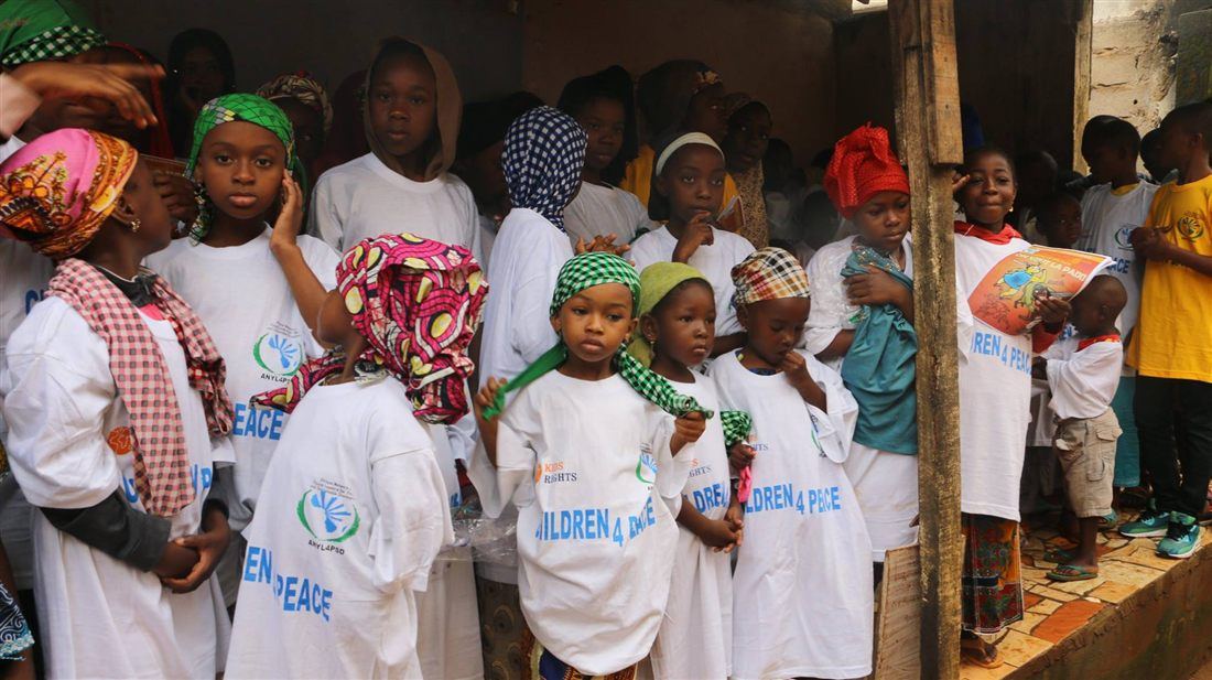 Children in white C4P t-shirts gathered indoors